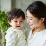 新札幌の清潔感ある歯科医院で、小児矯正の相談を笑顔で行う親子と、温かい自然光が差し込む院内風景