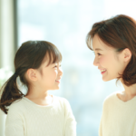 札幌の明るい歯科医院で、小児矯正の相談をして安心した表情で微笑み合う親子と温かい自然光の風景。