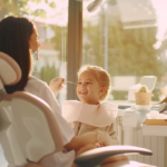 自然光が入る明るい歯科医院で、小児矯正について優しく相談に乗る歯科医師と安心した表情の親子