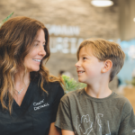 新札幌の明るい歯科医院で、小児矯正の相談を前に笑顔で向き合う親子と温かい自然光