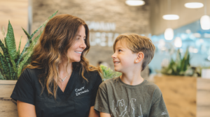 新札幌の明るい歯科医院で、小児矯正の相談を前に笑顔で向き合う親子と温かい自然光