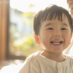 自然光が入る明るい空間で、笑顔を見せる親子。新札幌で小児矯正の相談を検討する際の安心感を表現。