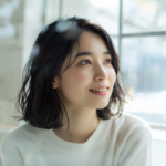 鏡の前で微笑む女性。新札幌・札幌でのライフスタイルに合わせた大人のマウスピース矯正をイメージ。