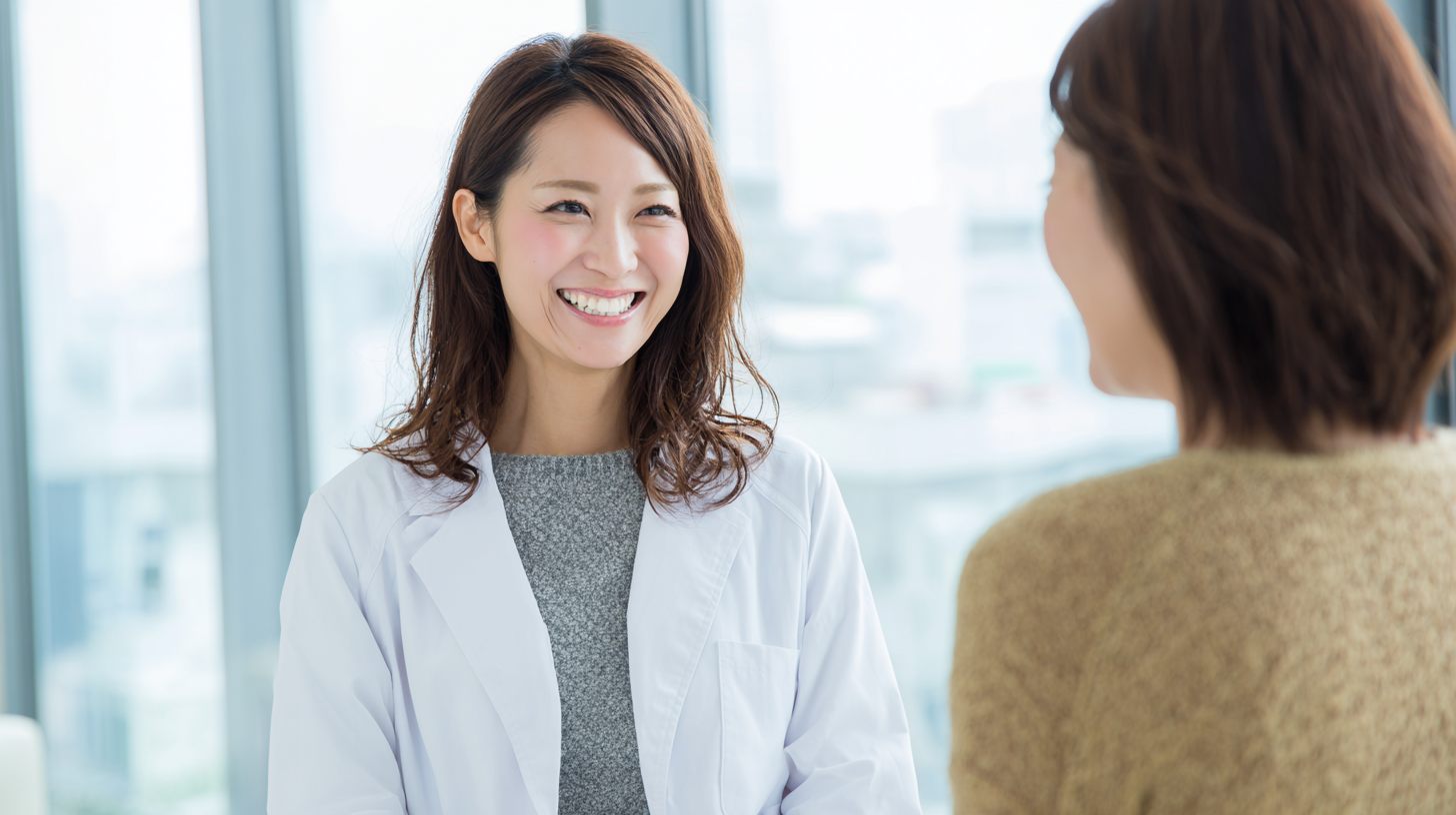 Smiling female clinician in a white coat speaks with a patient in a bright, modern clinic.