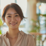 自然光が差し込む部屋でリラックスした笑顔を見せる30代女性。大人のマウスピース矯正の安心感を表現