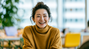 明るいオフィスで周囲の目を気にせず、笑顔で自然に会話を楽しむ大人の女性（マウスピース矯正のイメージ）