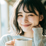 リラックスしてコーヒーを楽しむ女性。札幌・北広島での大人のマウスピース矯正をサポートします。