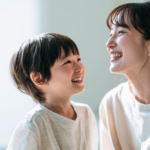 自然光が差し込む部屋で、安心した表情で笑顔で見つめ合う親子