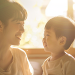 自然光の入る明るい部屋で、笑顔で見つめ合う親子の様子（小児矯正の相談）