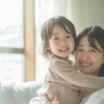 自然光が差し込む明るい部屋で穏やかに微笑み合う親子の姿と、小児矯正の判断整理を促すイメージ